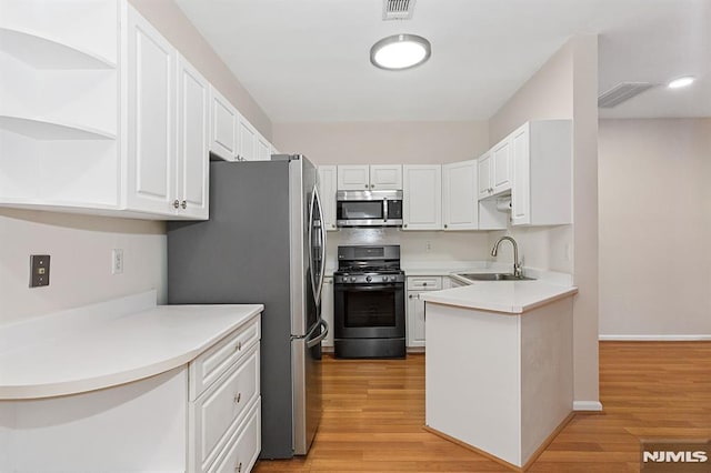 kitchen with white cabinets, sink, stainless steel appliances, and light hardwood / wood-style flooring