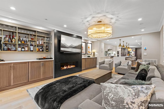 living room featuring light hardwood / wood-style floors, a notable chandelier, and ornamental molding