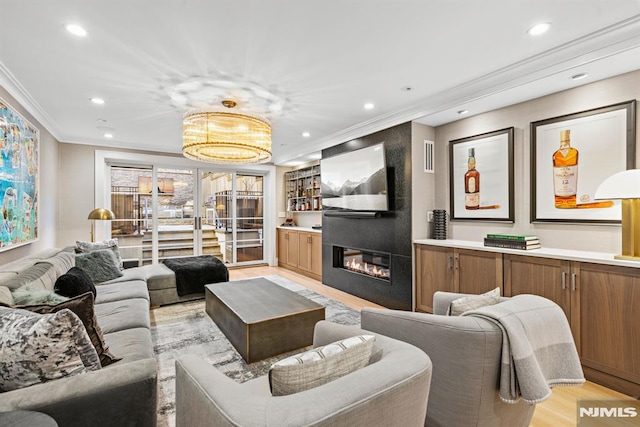 living room with a large fireplace, ornamental molding, and light hardwood / wood-style flooring