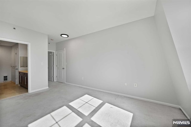 unfurnished bedroom featuring light carpet and connected bathroom