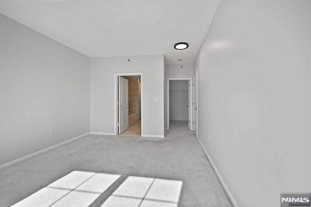 unfurnished bedroom with ensuite bath and light carpet