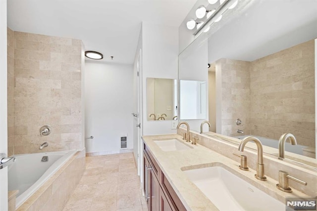 bathroom with tiled tub, tile patterned flooring, and vanity