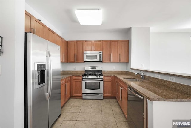 kitchen with light tile patterned flooring, sink, appliances with stainless steel finishes, and dark stone counters