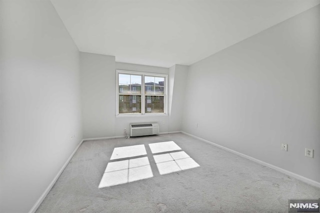 spare room featuring a wall mounted air conditioner and light colored carpet