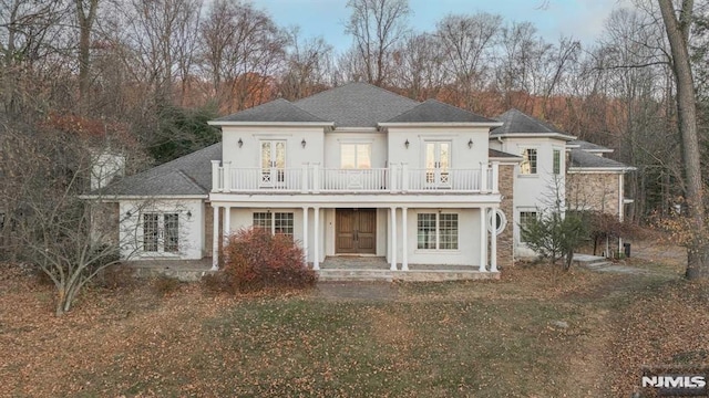 view of front facade with a front lawn, french doors, and a balcony