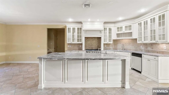 kitchen with light stone counters, ornamental molding, a center island with sink, dishwasher, and white cabinetry