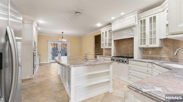 kitchen featuring sink, hanging light fixtures, stainless steel appliances, a kitchen island with sink, and white cabinets