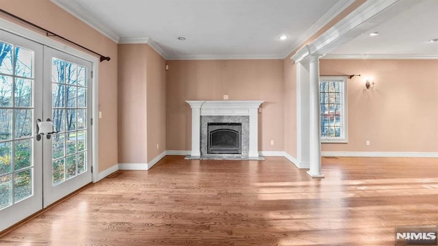 unfurnished living room with ornate columns, french doors, a high end fireplace, crown molding, and light hardwood / wood-style floors