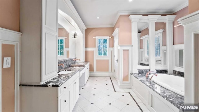 bathroom with a bathing tub, vanity, ornate columns, and ornamental molding