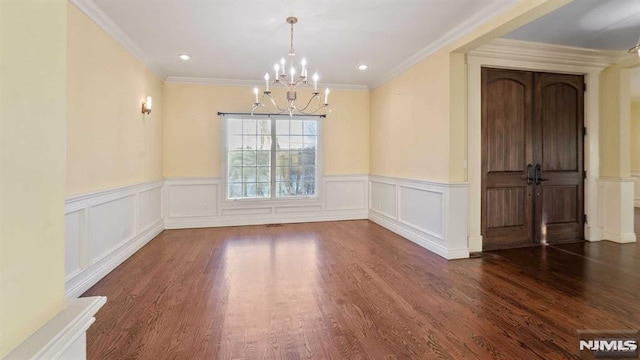 unfurnished dining area with dark hardwood / wood-style floors, crown molding, and a chandelier