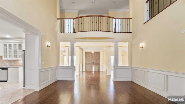 foyer entrance with decorative columns, wood-type flooring, and ornamental molding