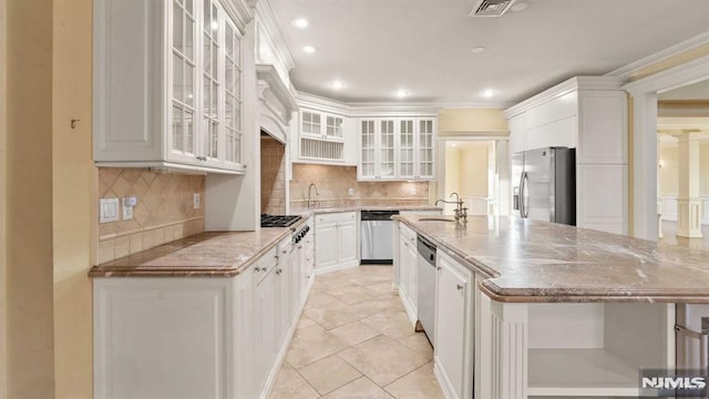 kitchen with light stone countertops, sink, stainless steel appliances, tasteful backsplash, and white cabinets