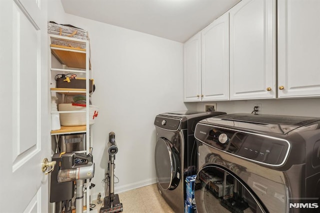 clothes washing area featuring cabinets and separate washer and dryer