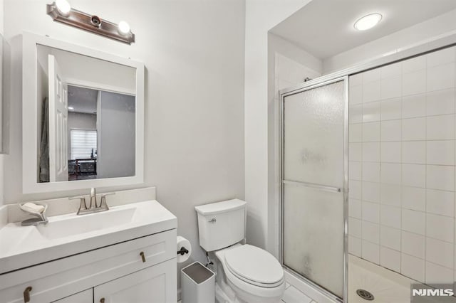 bathroom with a shower with door, vanity, and toilet