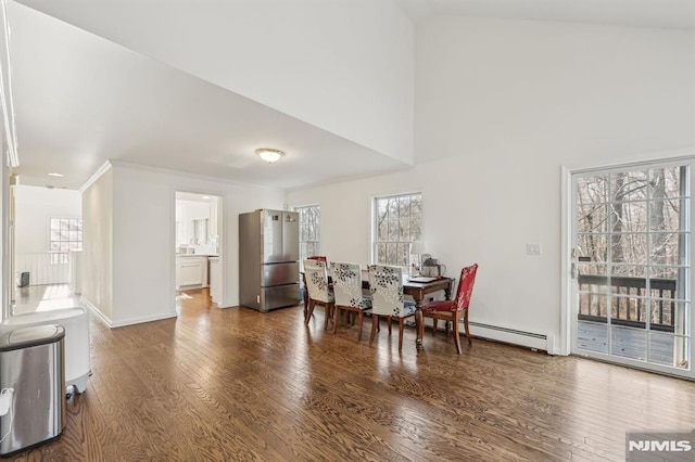 dining area featuring a towering ceiling, dark wood-type flooring, and a baseboard heating unit