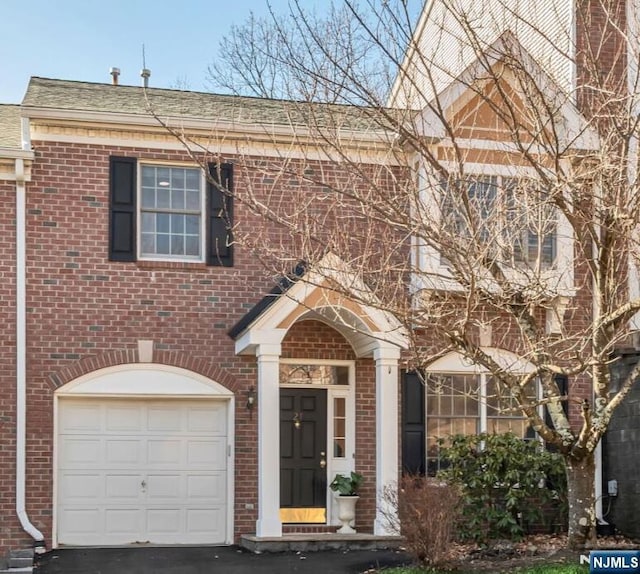 view of front of house with brick siding, a shingled roof, aphalt driveway, and a garage