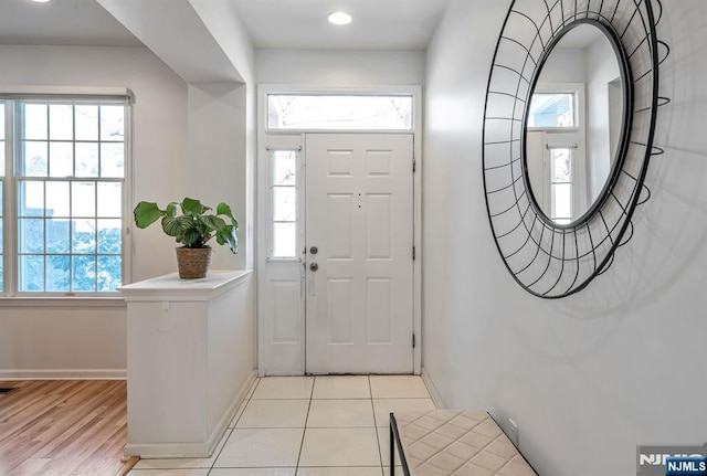 foyer featuring light tile patterned floors, baseboards, and a wealth of natural light