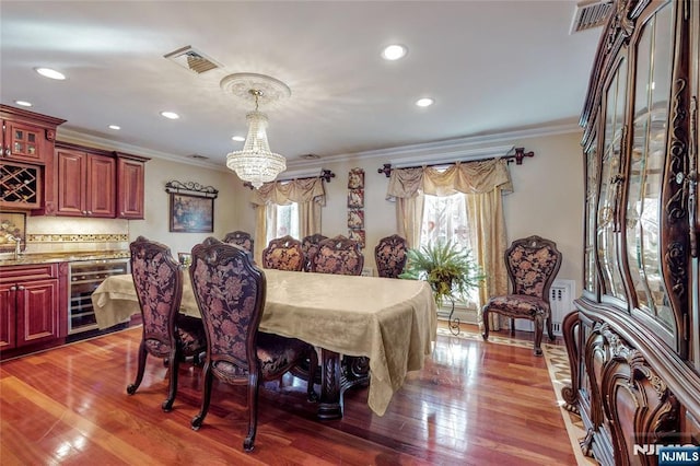 dining space featuring crown molding, plenty of natural light, beverage cooler, and a chandelier