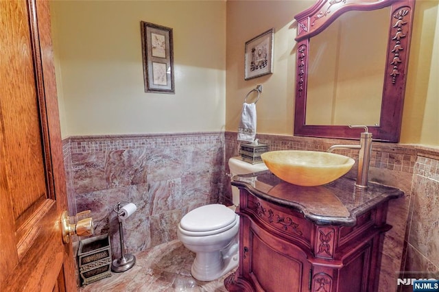 bathroom with vanity, tile walls, and toilet