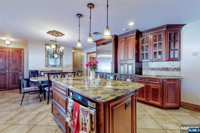 kitchen featuring light stone counters, decorative light fixtures, a kitchen breakfast bar, a kitchen island, and backsplash