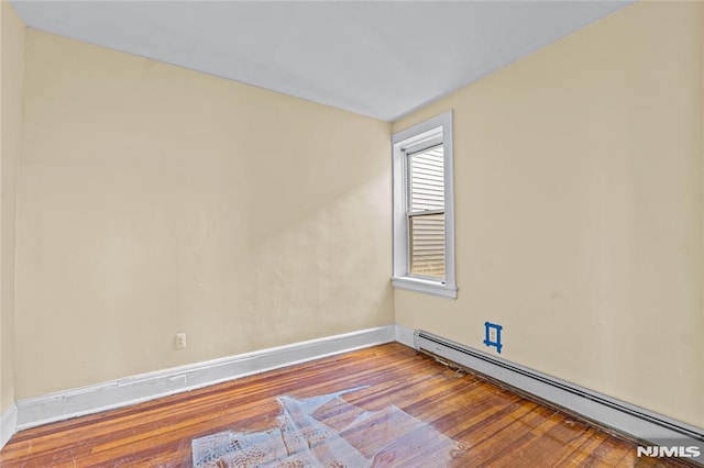 unfurnished room with wood-type flooring and baseboard heating