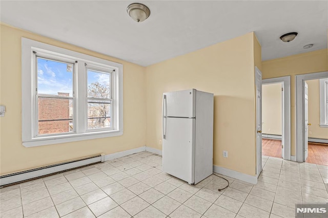 kitchen featuring light tile patterned floors, white fridge, and a baseboard heating unit