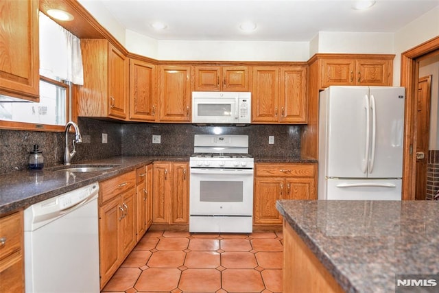 kitchen featuring decorative backsplash, white appliances, sink, and dark stone counters