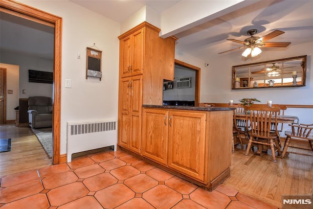 kitchen featuring ceiling fan, a wall unit AC, kitchen peninsula, and radiator