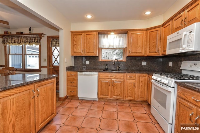 kitchen featuring tasteful backsplash, sink, dark stone counters, and white appliances