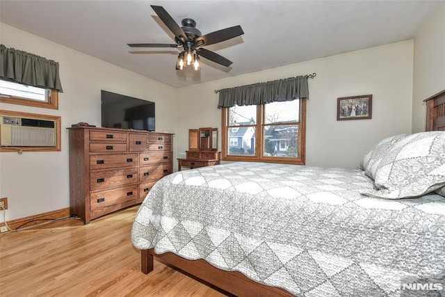 bedroom with a wall mounted AC, hardwood / wood-style flooring, and ceiling fan