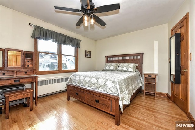 bedroom with ceiling fan, radiator heating unit, and light wood-type flooring