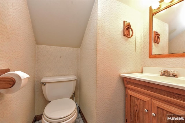 bathroom featuring vanity, lofted ceiling, and toilet