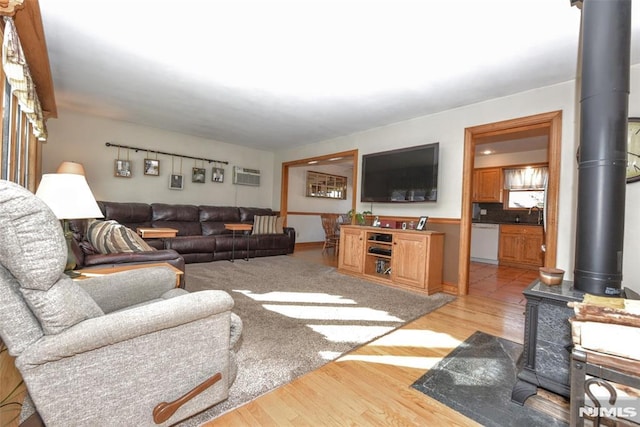 living room featuring a wall mounted air conditioner, light wood-type flooring, and a wood stove