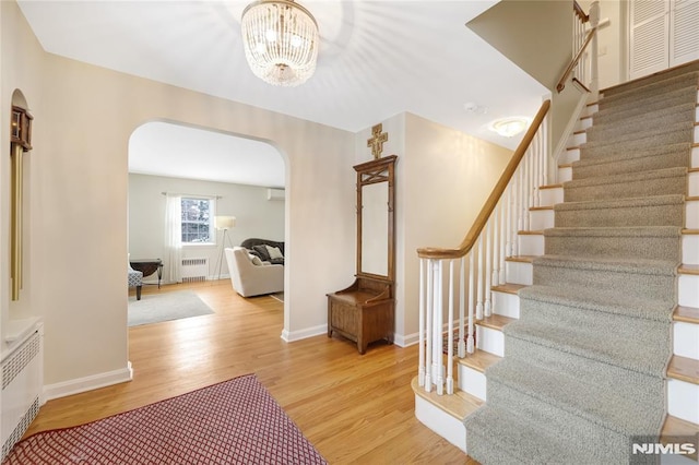 interior space with light wood-type flooring, radiator, and an inviting chandelier