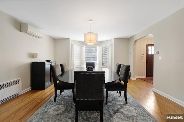 dining room with hardwood / wood-style floors, radiator, and a wall mounted AC