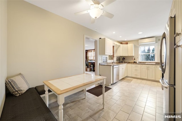 kitchen with stainless steel appliances, sink, a wall mounted AC, light tile patterned flooring, and ceiling fan