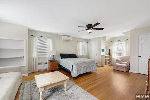 bedroom featuring ceiling fan, radiator heating unit, hardwood / wood-style floors, and a wall unit AC