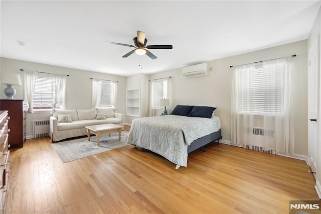 bedroom with a wall mounted air conditioner, radiator heating unit, ceiling fan, and wood-type flooring