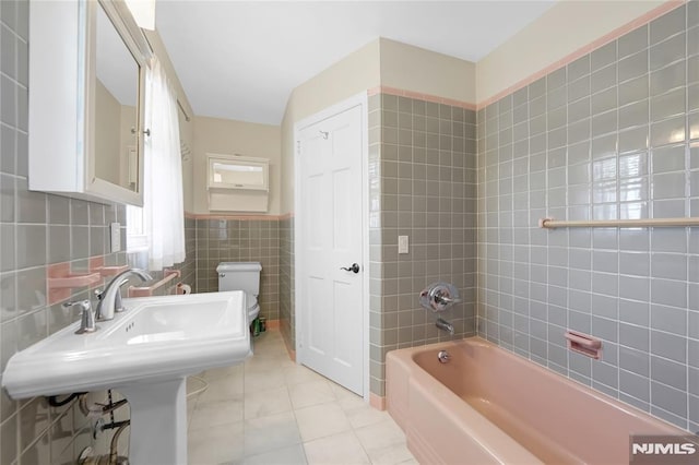 full bathroom with tiled shower / bath, tile patterned flooring, sink, tile walls, and toilet