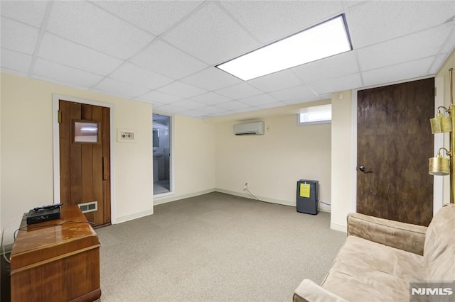 basement featuring a paneled ceiling, a wall mounted AC, and carpet