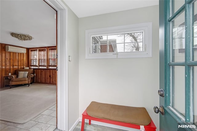 doorway featuring an AC wall unit, wooden walls, and light carpet