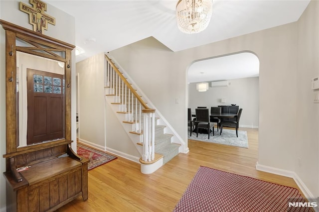 entryway featuring hardwood / wood-style flooring, an AC wall unit, and a chandelier