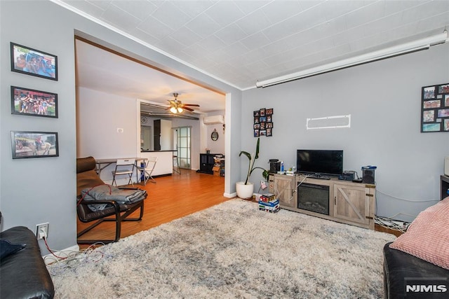 living room featuring hardwood / wood-style floors, ceiling fan, and ornamental molding