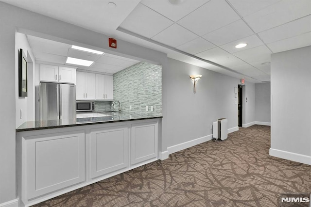 kitchen featuring white cabinets, decorative backsplash, stainless steel appliances, and a drop ceiling