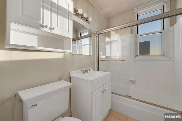 full bathroom with tile patterned flooring, vanity, bath / shower combo with glass door, and toilet