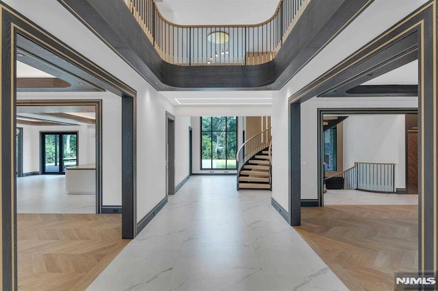 hall featuring light parquet floors, a towering ceiling, a healthy amount of sunlight, and french doors