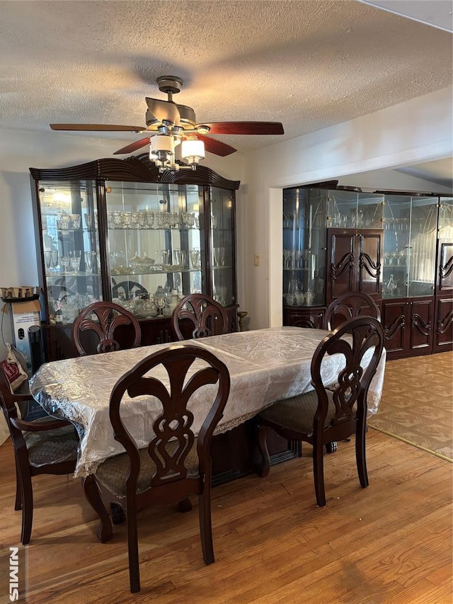 dining room with a textured ceiling, hardwood / wood-style flooring, and ceiling fan