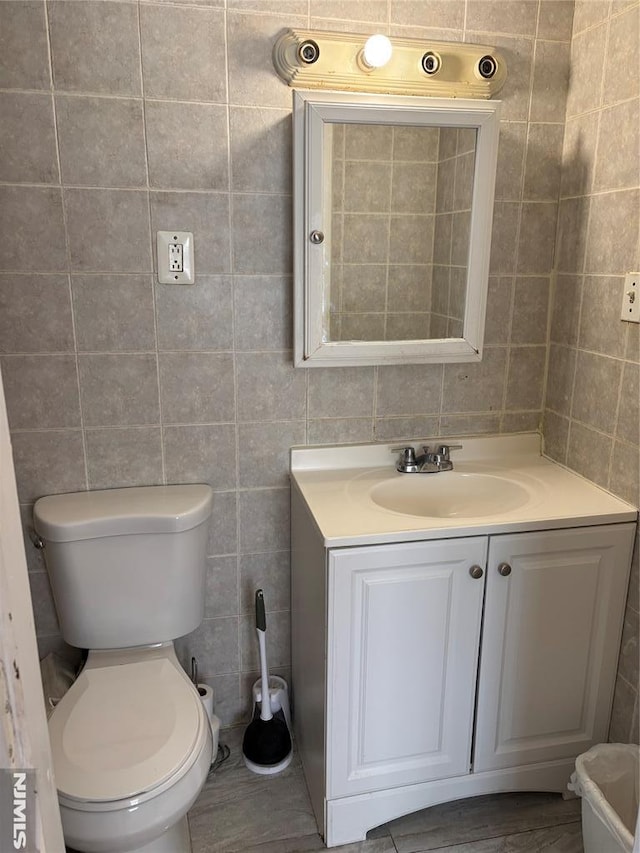 bathroom featuring vanity, toilet, and tile walls