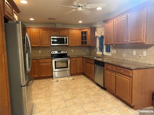 kitchen with sink, ceiling fan, dark stone countertops, appliances with stainless steel finishes, and light tile patterned flooring