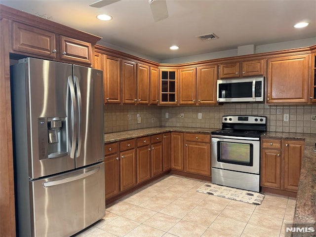 kitchen featuring light tile patterned flooring, dark stone counters, and appliances with stainless steel finishes